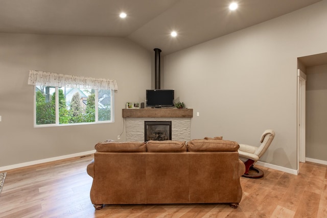 living room with light hardwood / wood-style flooring, lofted ceiling, and a fireplace