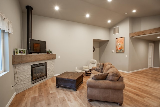 living room with a fireplace, high vaulted ceiling, and light hardwood / wood-style floors