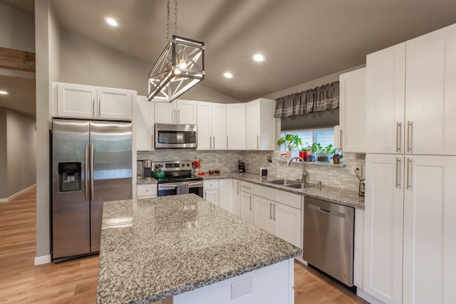 kitchen with sink, a kitchen island, white cabinetry, stainless steel appliances, and lofted ceiling