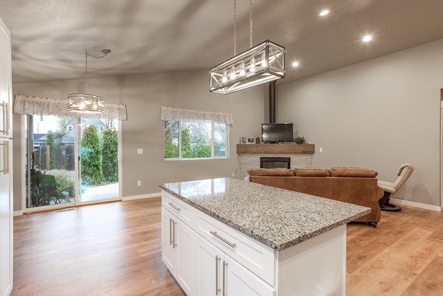 kitchen with white cabinetry, hanging light fixtures, light wood-type flooring, and vaulted ceiling