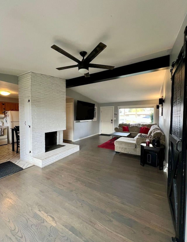 unfurnished living room featuring vaulted ceiling with beams, wood-type flooring, a barn door, a fireplace, and ceiling fan