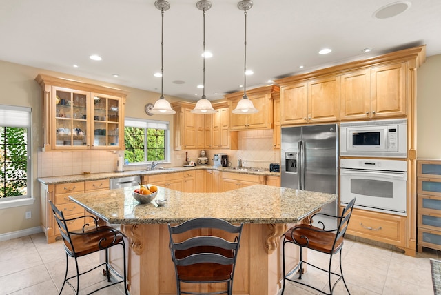 kitchen with a kitchen island, a kitchen breakfast bar, stainless steel appliances, sink, and light stone countertops