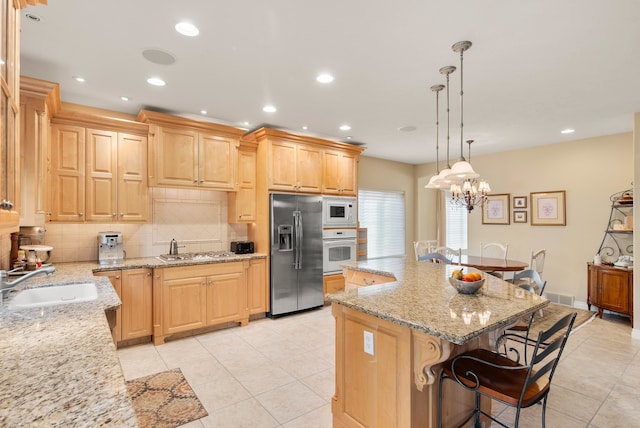 kitchen with sink, appliances with stainless steel finishes, light stone counters, and a kitchen island