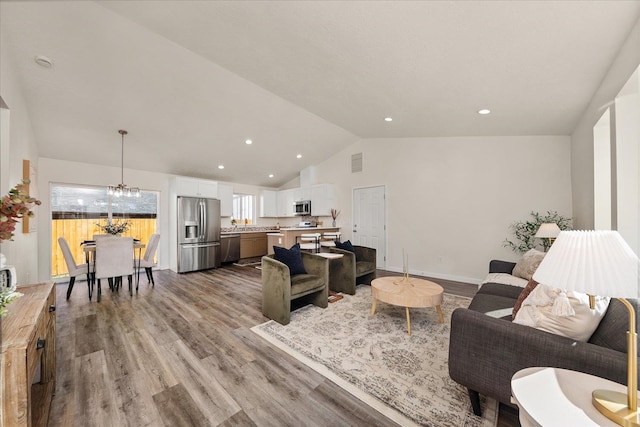 living room featuring lofted ceiling, a chandelier, and wood-type flooring