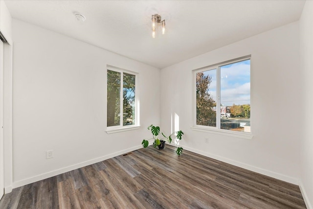 spare room with a wealth of natural light and dark wood-type flooring