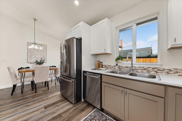 kitchen with appliances with stainless steel finishes, sink, backsplash, hardwood / wood-style floors, and lofted ceiling