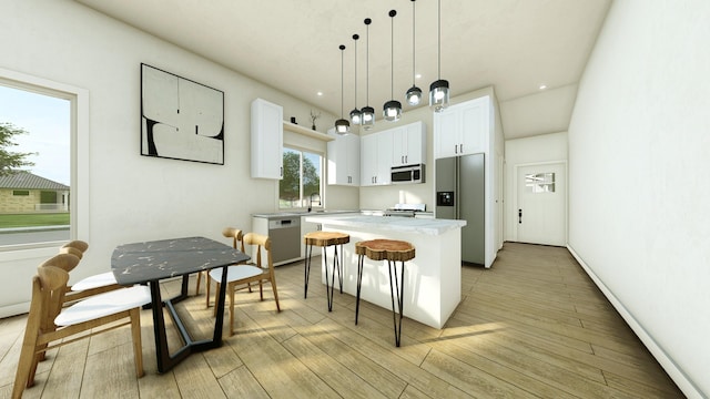 kitchen featuring appliances with stainless steel finishes, light wood-type flooring, a kitchen island, hanging light fixtures, and white cabinetry