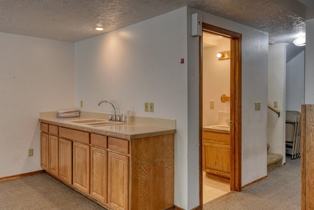 kitchen featuring sink, light colored carpet, and a textured ceiling