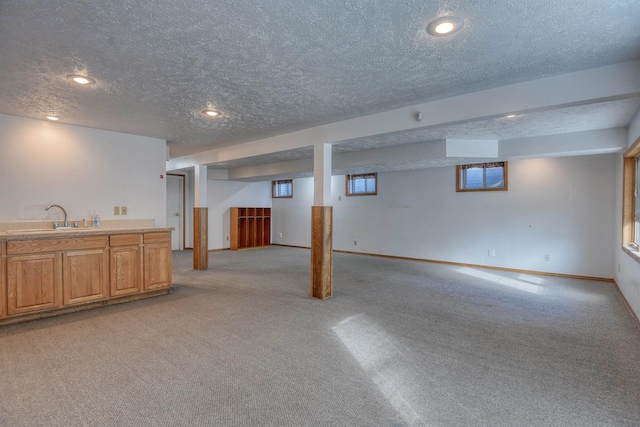 basement with light colored carpet, a textured ceiling, and sink