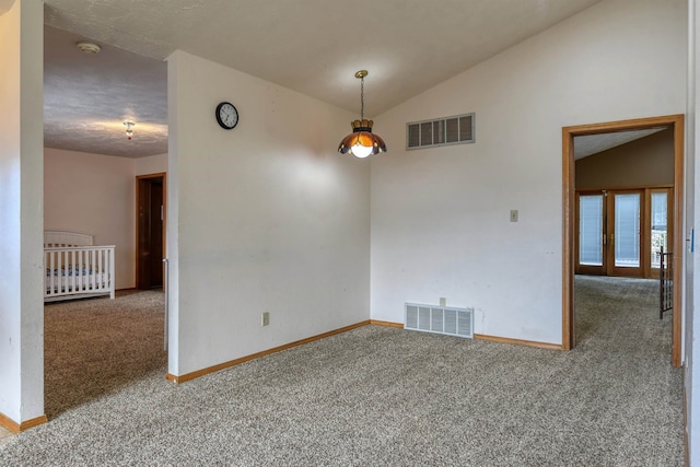 spare room featuring a textured ceiling, vaulted ceiling, and carpet floors