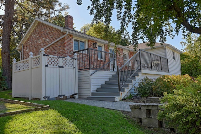3224 E 28th Ave, Spokane, WA 99223 - back of house featuring a chimney, a wooden deck, a lawn, brick siding, and stairs