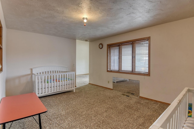 bedroom with carpet flooring, a textured ceiling, and a nursery area