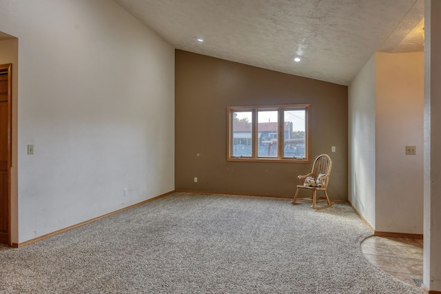 spare room featuring light carpet, a textured ceiling, and vaulted ceiling