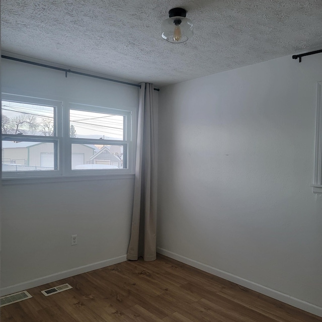 unfurnished room with dark hardwood / wood-style floors and a textured ceiling