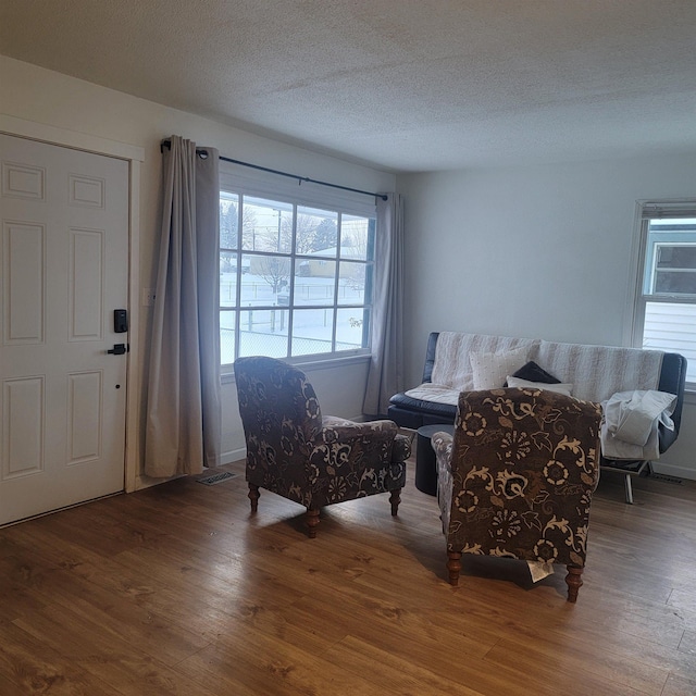 living area with a wealth of natural light, a textured ceiling, and wood finished floors