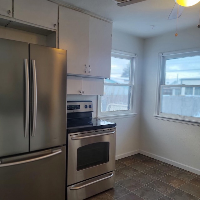 kitchen with ceiling fan, appliances with stainless steel finishes, dark tile patterned floors, and white cabinets