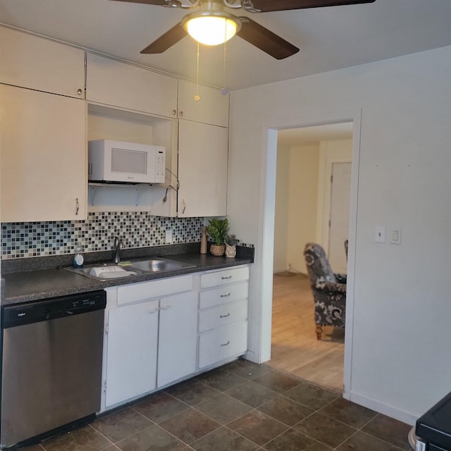 kitchen with tasteful backsplash, dishwasher, dark countertops, white microwave, and a sink