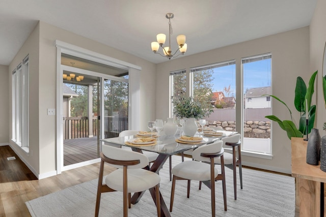 dining space featuring a chandelier, wood finished floors, and baseboards
