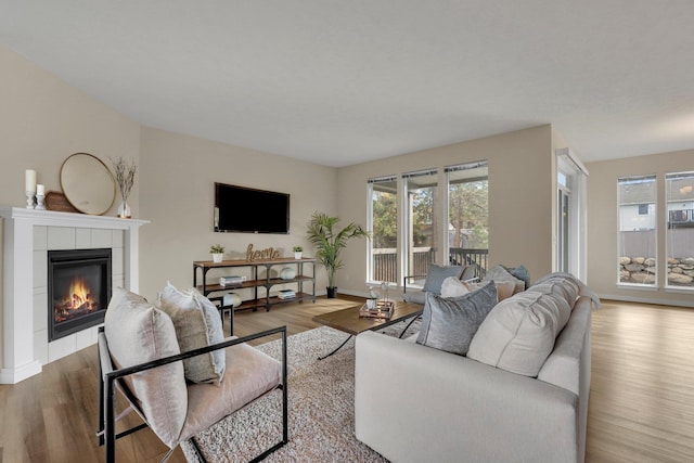 living area with a tile fireplace, wood finished floors, and baseboards
