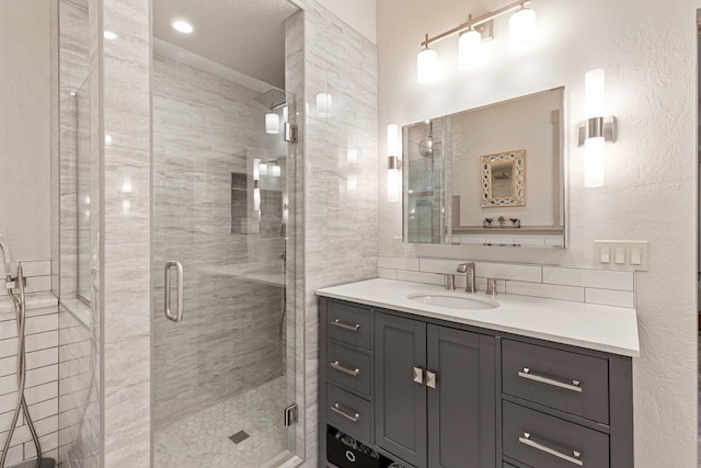 bathroom with a shower with door, vanity, and tasteful backsplash