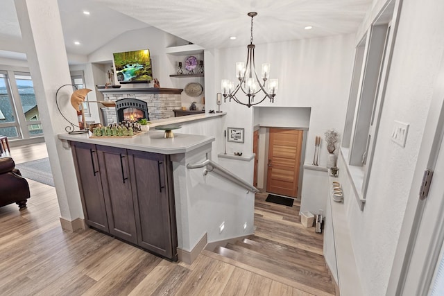 kitchen featuring light hardwood / wood-style floors, decorative light fixtures, dark brown cabinets, and vaulted ceiling