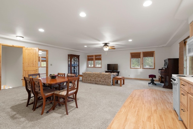 carpeted dining room featuring crown molding and ceiling fan