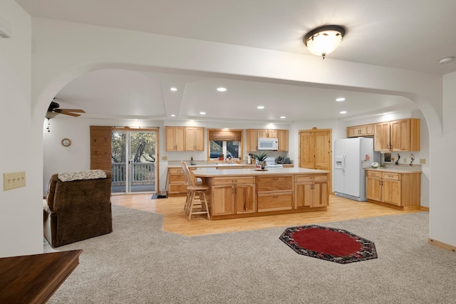 kitchen featuring white appliances, a center island, and light hardwood / wood-style flooring