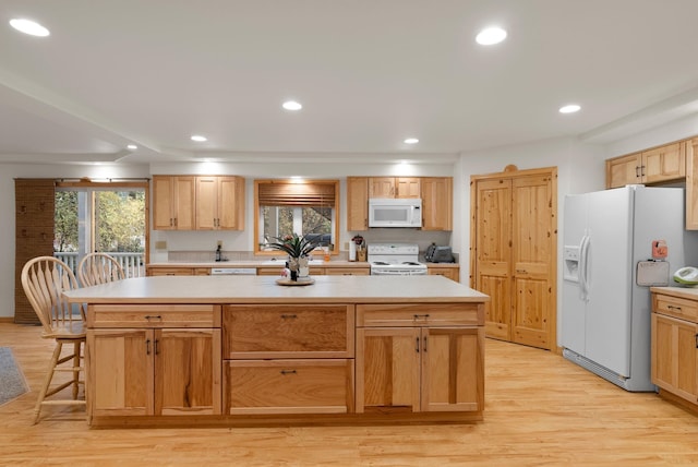 kitchen with a kitchen island, light hardwood / wood-style flooring, a kitchen bar, and white appliances