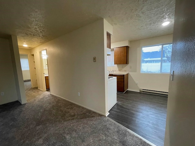 unfurnished room with dark hardwood / wood-style floors, a textured ceiling, and a baseboard heating unit