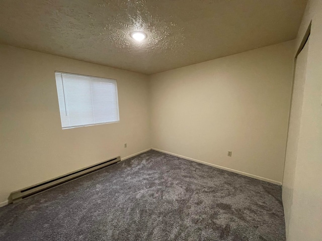 carpeted spare room with a textured ceiling and a baseboard heating unit