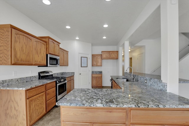 kitchen with kitchen peninsula, appliances with stainless steel finishes, sink, and light stone countertops