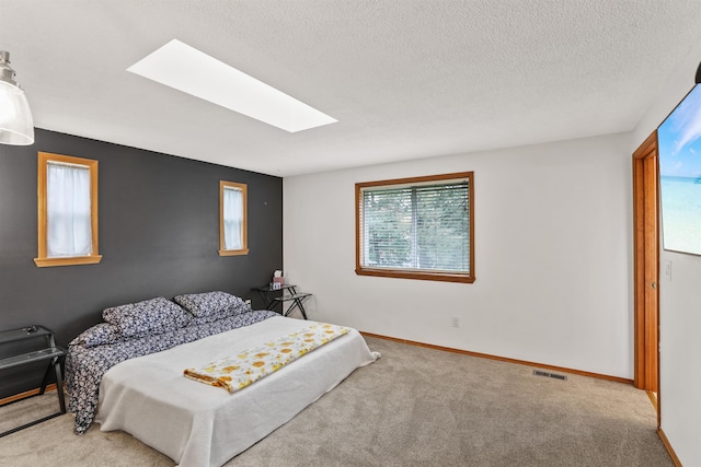 carpeted bedroom with a skylight and a textured ceiling