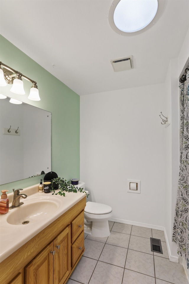 bathroom with toilet, vanity, and tile patterned floors