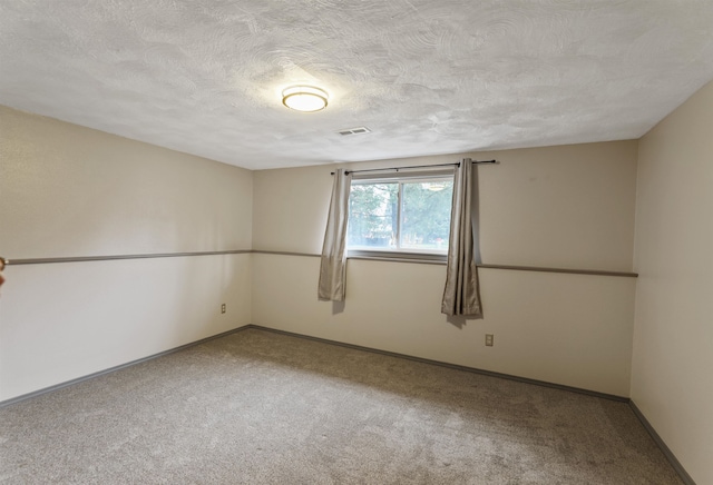 carpeted empty room featuring a textured ceiling