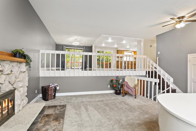 interior space with ceiling fan, a stone fireplace, and lofted ceiling