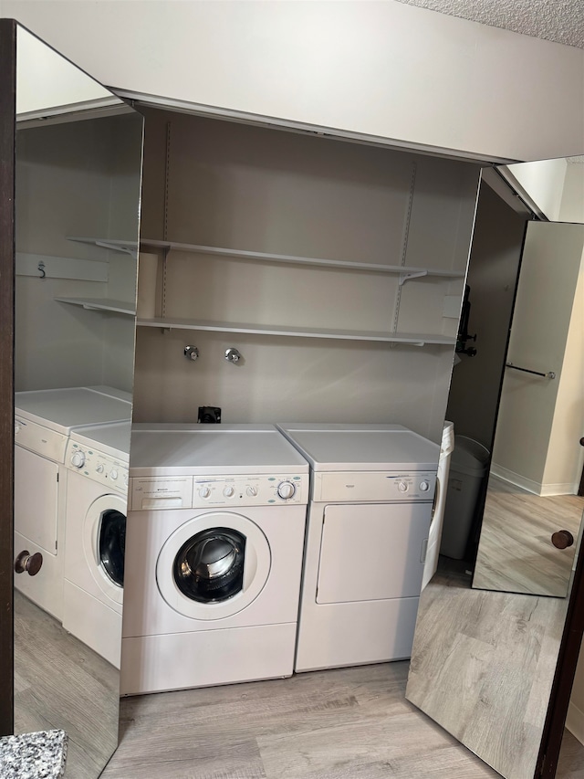 laundry area with washer and clothes dryer, a textured ceiling, and light hardwood / wood-style floors