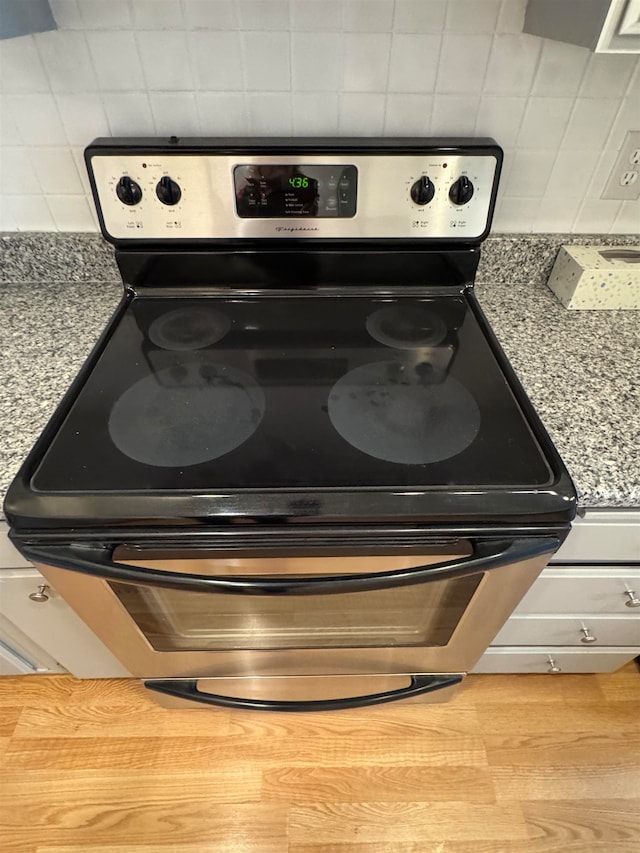 room details with light stone countertops, stainless steel stove, and tasteful backsplash