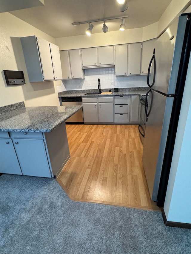 kitchen with stainless steel appliances, light hardwood / wood-style floors, sink, gray cabinetry, and decorative backsplash