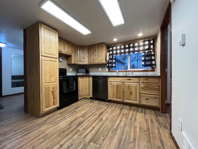 kitchen featuring hardwood / wood-style floors, black appliances, and sink