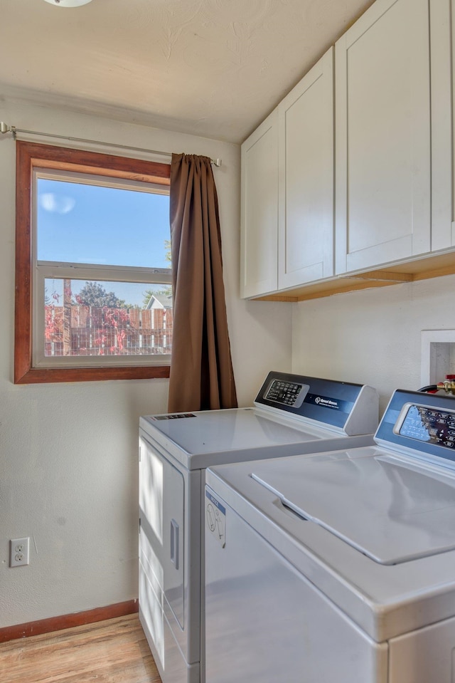 clothes washing area with light hardwood / wood-style flooring, washer and clothes dryer, and cabinets