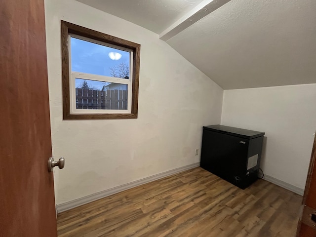 additional living space with wood-type flooring and vaulted ceiling