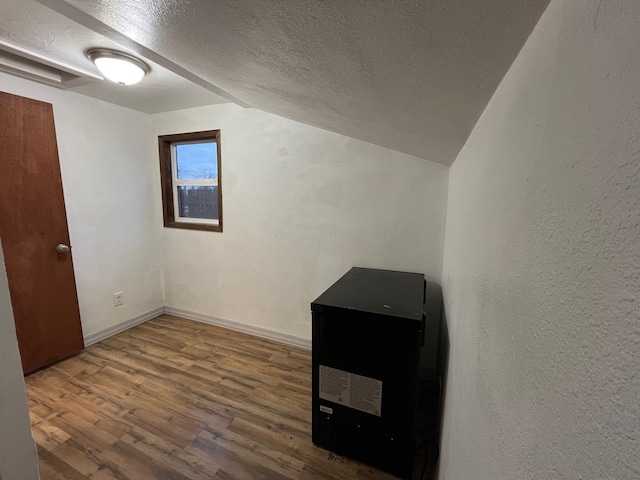 bonus room with wood-type flooring, a textured ceiling, and vaulted ceiling