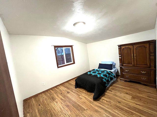 bedroom featuring hardwood / wood-style flooring and lofted ceiling