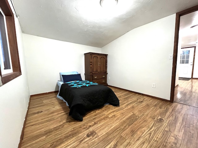 bedroom with hardwood / wood-style flooring and lofted ceiling