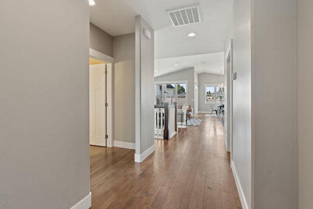 corridor with hardwood / wood-style floors and lofted ceiling