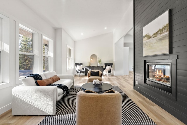 living room featuring a fireplace, light hardwood / wood-style flooring, and lofted ceiling