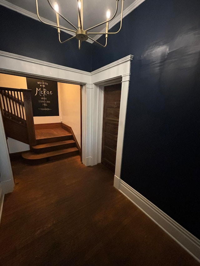 hallway with a chandelier, a high ceiling, dark hardwood / wood-style flooring, and ornamental molding