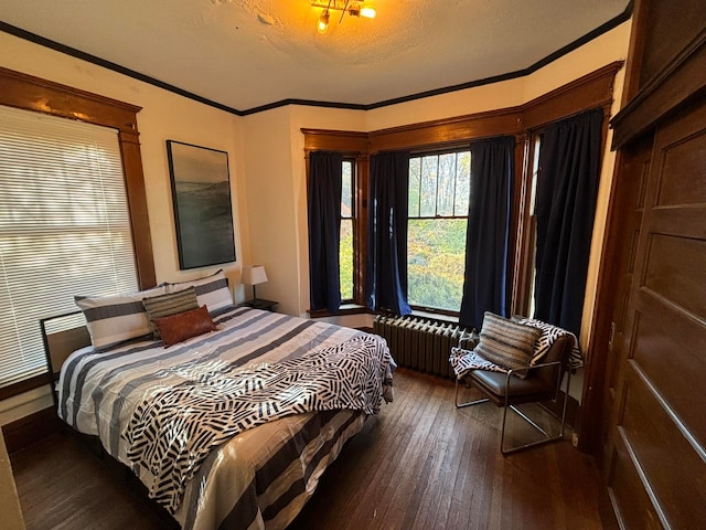 bedroom with a textured ceiling, crown molding, radiator heating unit, and dark wood-type flooring