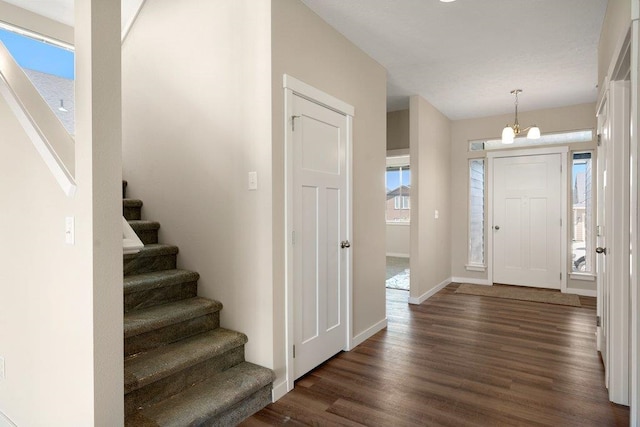 entrance foyer with dark hardwood / wood-style floors, plenty of natural light, and a chandelier