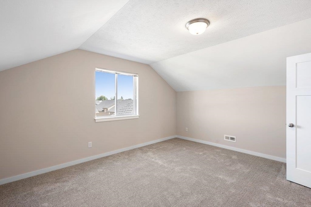 bonus room featuring light colored carpet, a textured ceiling, and vaulted ceiling